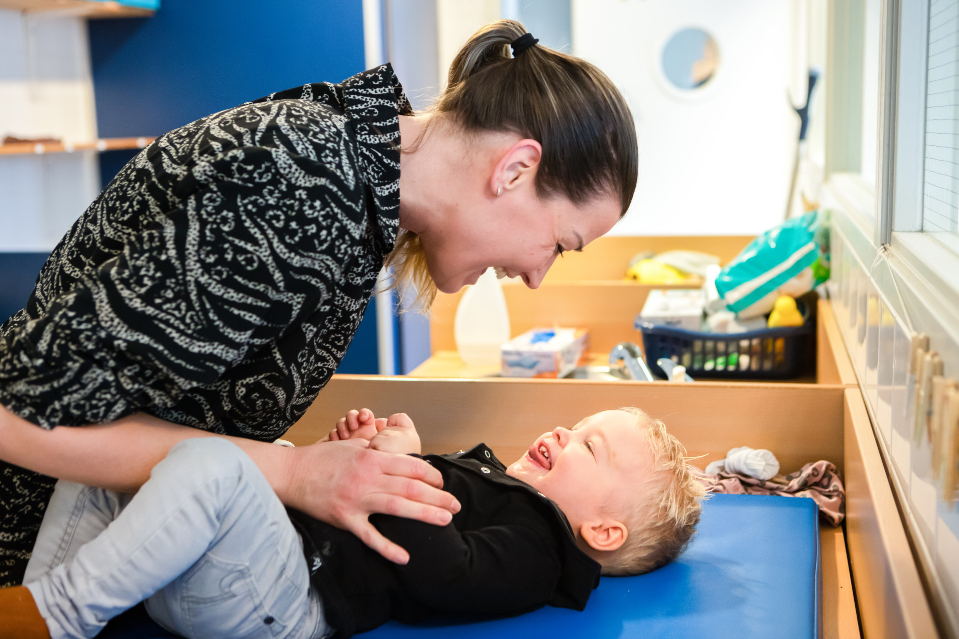 pedagogisch medewerker en peuter lachen naar elkaar