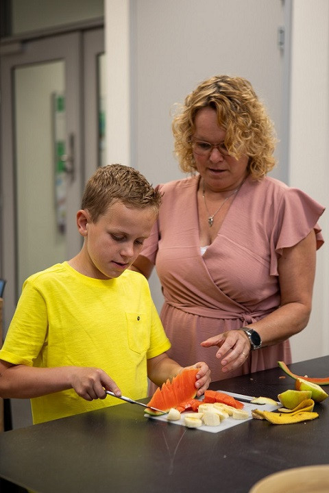 jongen en pedagogisch medewerker snijden fruit