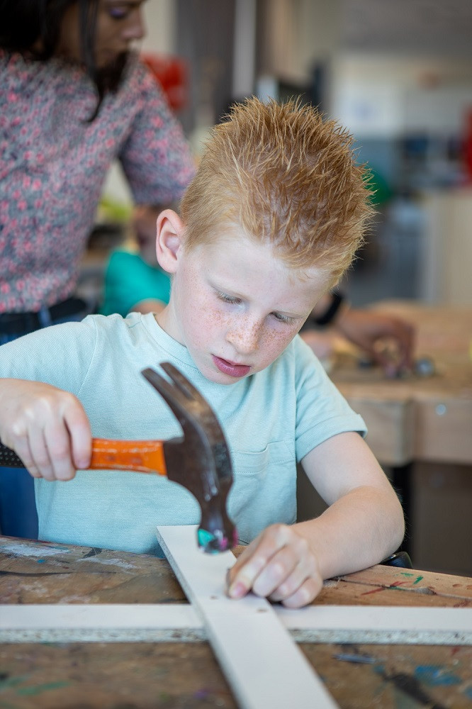kind slaat spijker in plankje