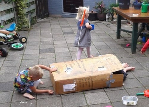 kinderen spelen buiten met kartonnen doos