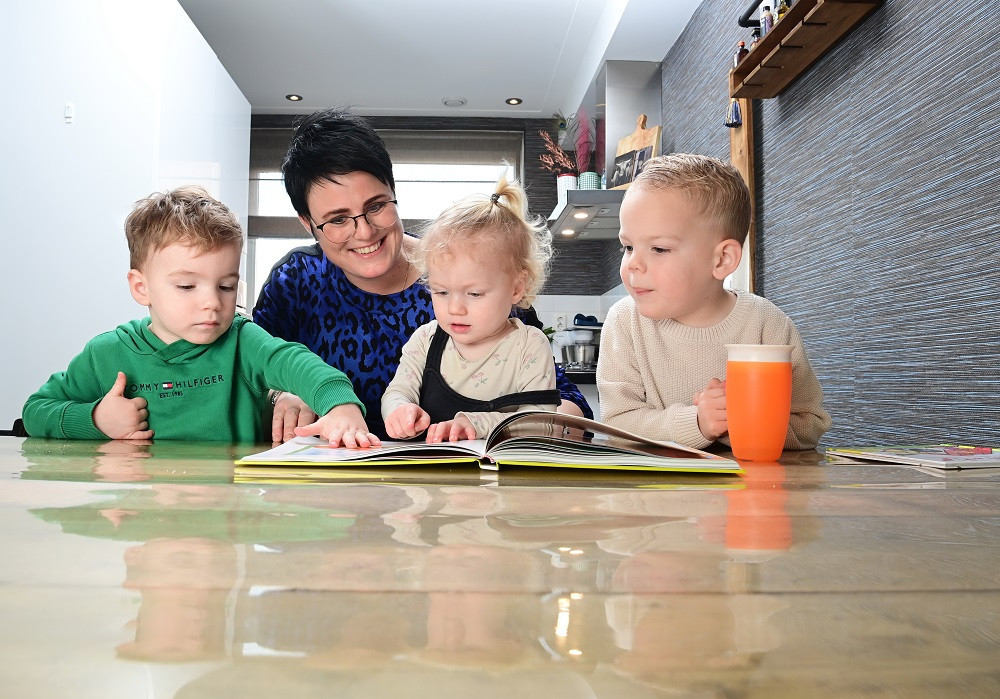 kinderen lezen een boek met een gastouder