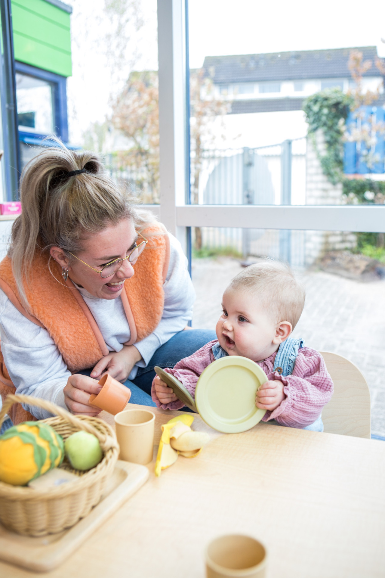 Pedagogisch medewerker en kind spelen aan tafel met bord
