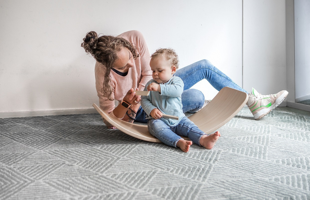 Pedagogisch medewerker geeft blokje aan kind