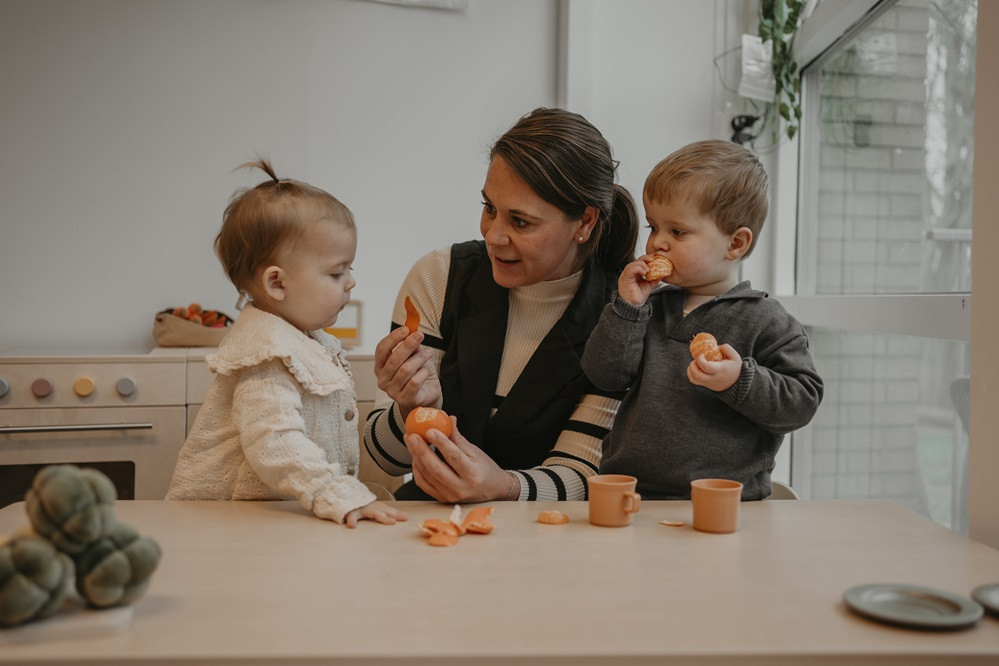 Pedagogisch professional eet mandarijnen met peuters