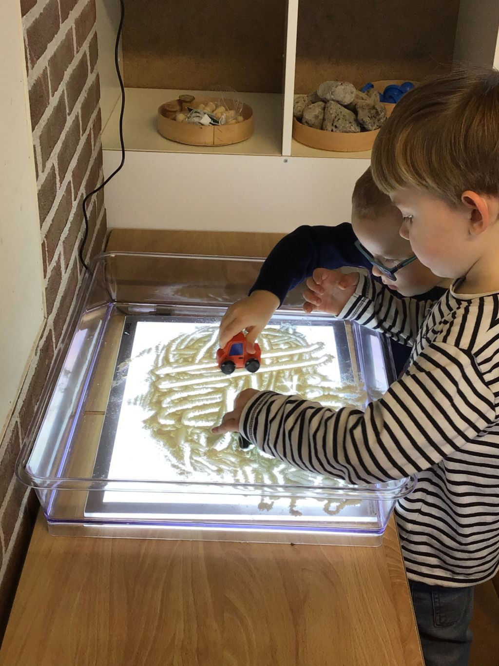Kinderen spelen met autootjes in lichtbak