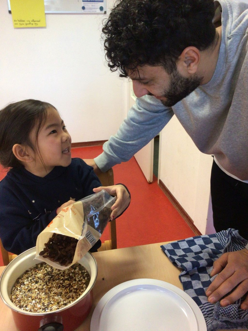 kind helpt pedagogisch professional met koken