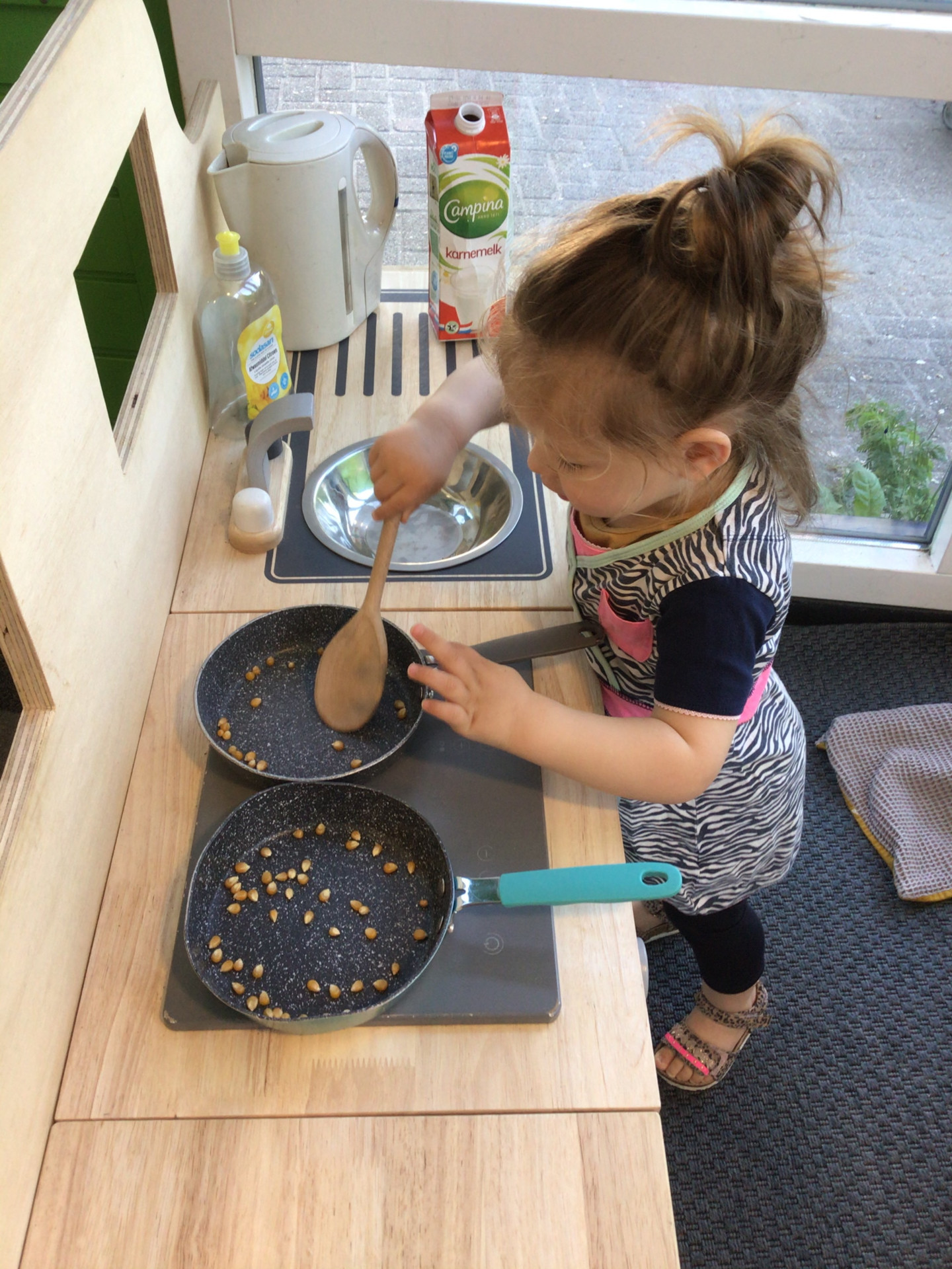 meisje speelt in de keuken met pannen