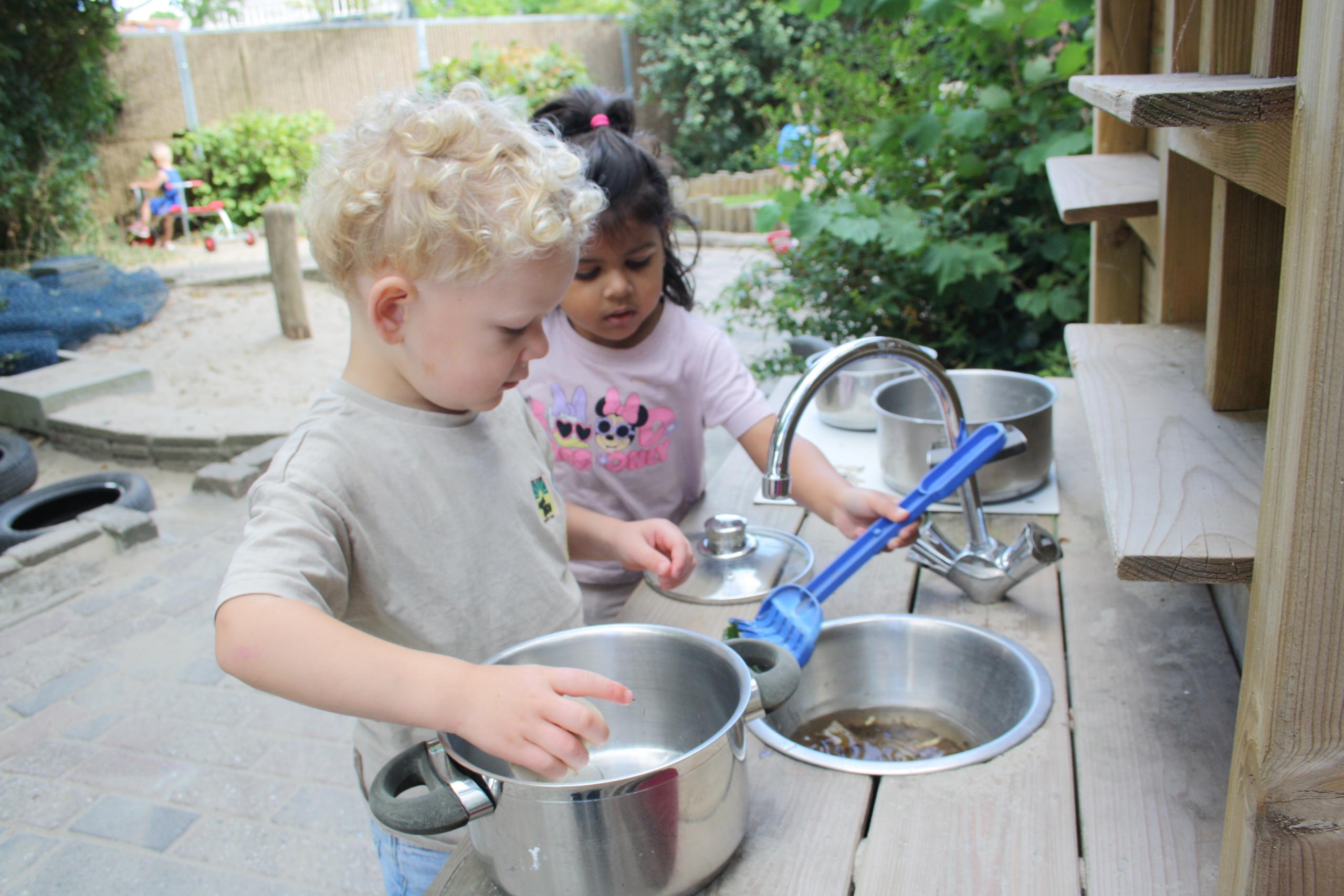 Twee peuters spelen in de buitenkeuken