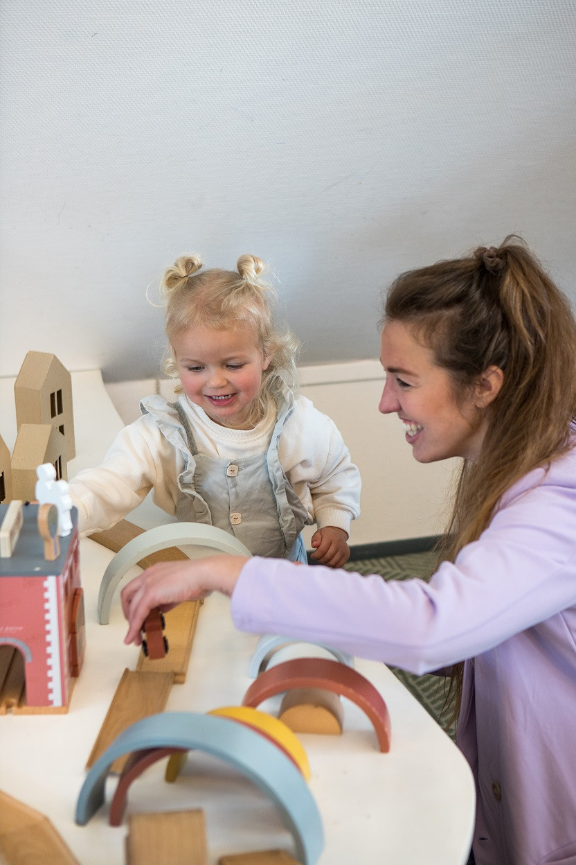 pedagogisch professional speelt met peuter