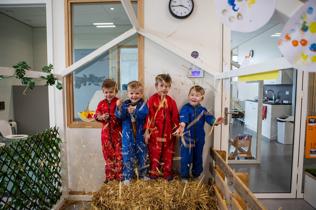kinderen in overalls die gooien met hooi