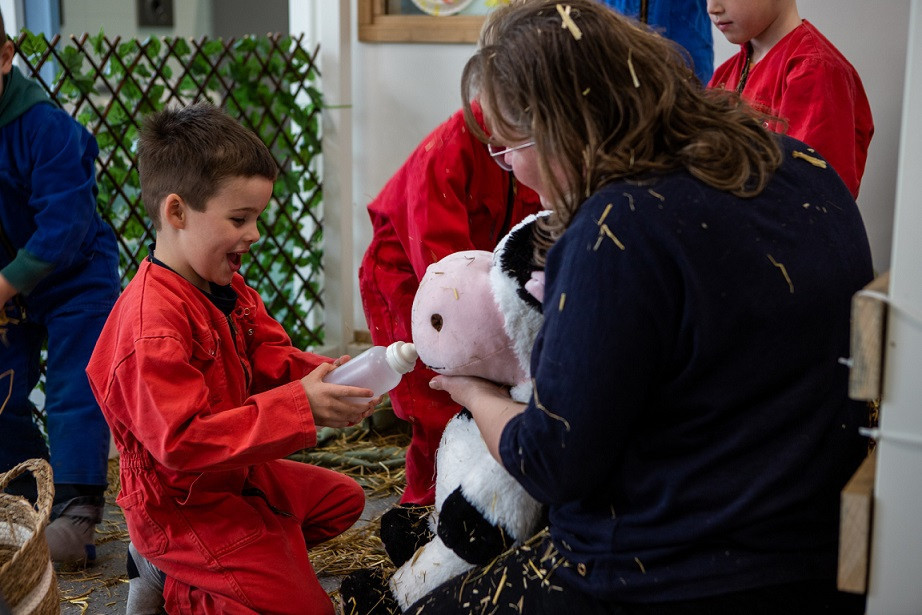 jongen geeft knuffelkoe een fles