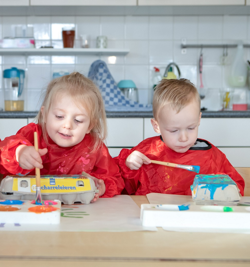 twee peuters schilderen eierdoos