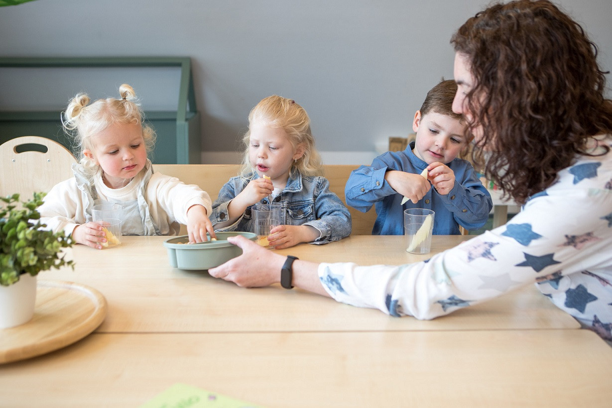 pedagogisch professional deelt fruit uit aan peuters