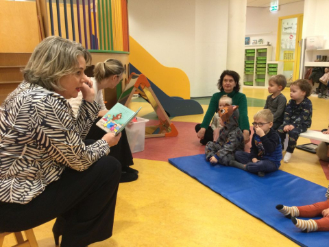 Kinderen worden voorgelezen en zitten op grond
