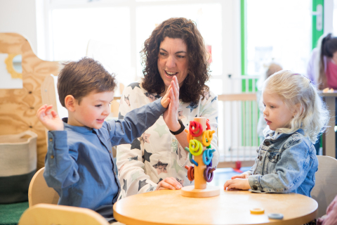 kinderen spelen aan tafel met pedagogisch medewerker