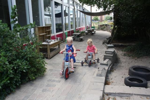 kinderen fietsen in de tuin bij kinderdagverblijf de goorn
