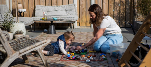 Gastouder en kind spelen op grond buiten