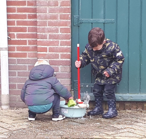 kinderen spelen met bezem en water