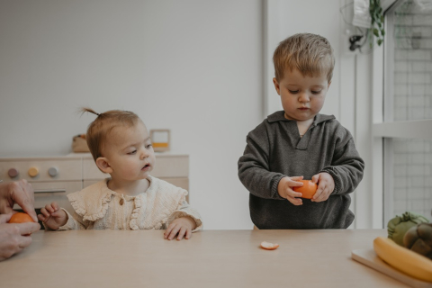 Een peuter pelt een mandarijn