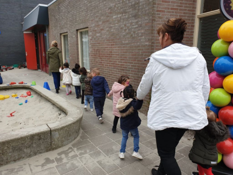 kinderen lopen in een rij over het plein