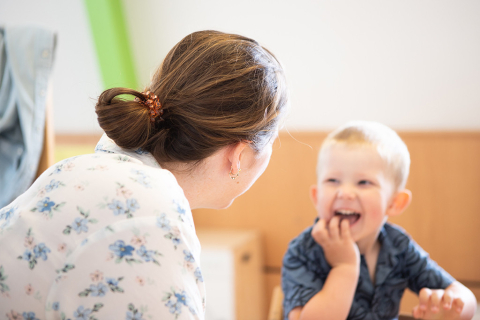 peuter lacht blij naar pedagogisch professional