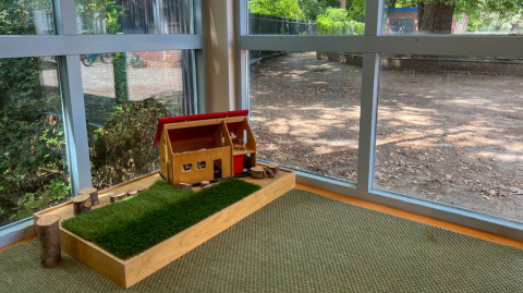 Houten speelhuis op kunstgras bij kinderdagverblijf Boevenhoeve in Opmeer.