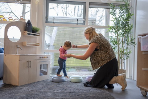 Pedagogisch professional helpt kind over blokken te lopen