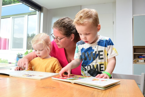 Gastouder leest boekje met kinderen