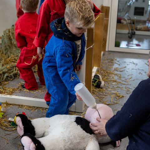 kind geeft knuffelkoe een fles
