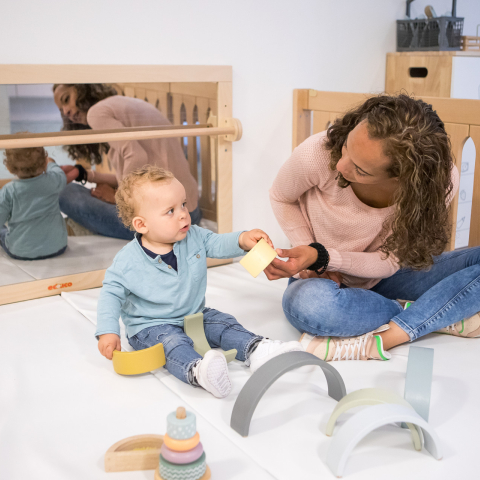 pedagogisch medewerker en dreumes spelen in de grondbox