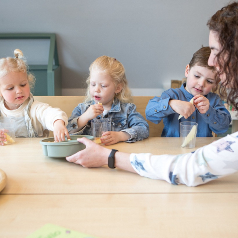 pedagogisch professional deelt fruit uit aan peuters