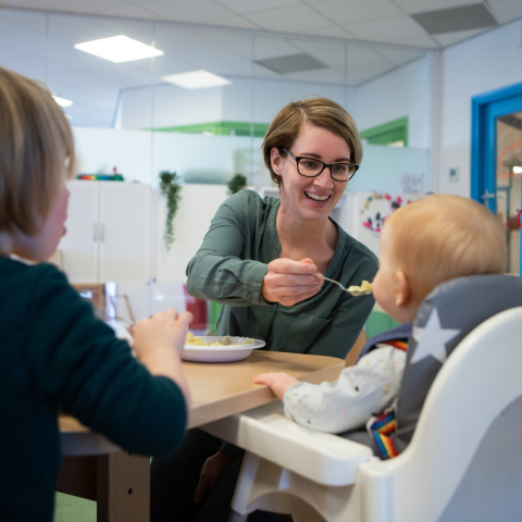 pedagogisch medewerker geeft kind eten