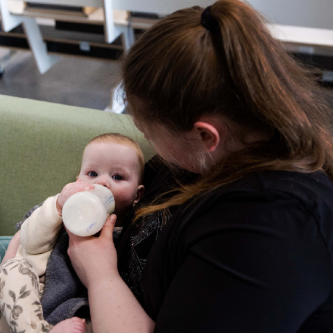pedagogisch professional geeft baby fles