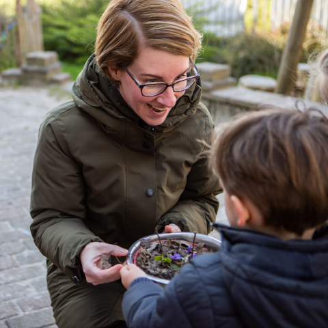 pedagogisch medewerker speelt buiten met peuter